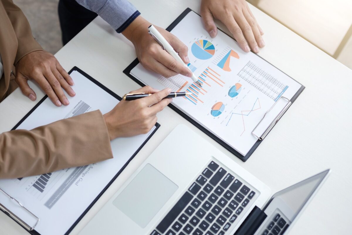 Man and woman standing over a desk reviewing charts and graphs