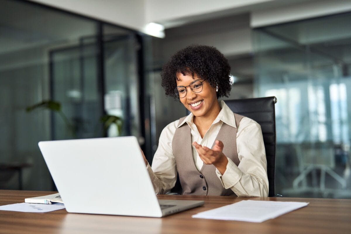 Professional young woman sitting at a desk and engaged in an online meeting